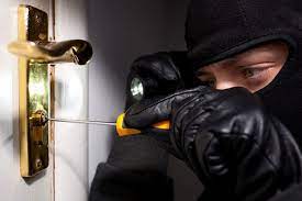 Na zdjęciu zamaskowany mężczyzna próbujący otworzyć okno za pomocą śrubokręta