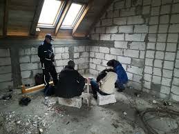 policjant umundurowany stoi w pustostanie, obok siedzą osoby bezdomne