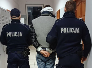 zatrzymany do kradzieży samochodu stoi tyłem, obok niego umundurowani policjanci