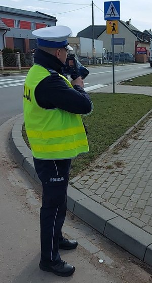 Umundurowany policjant kontroluje prędkość w rejonie przejścia dla pieszych