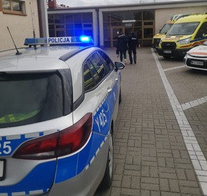 policjant prowadzący kobietę w ciąży do wejścia do szpitala
