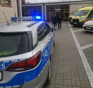 policjant prowadzący kobietę w ciąży do wejścia do szpitala