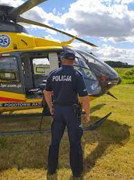 Policjant stoi tyłem, przed nim helikopter LPR