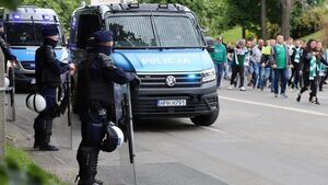 Policjanci umundurowani, obok radiowozy