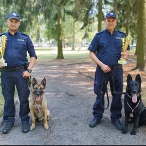 na zdjęciu przewodnicy psów służbowych trzymający w ręce puchary i policyjne czworonogi