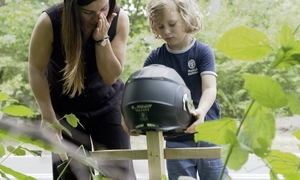 kask motocyklowy na krzyżu, w tle dziecko i kobieta