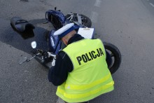 policjant na miejscu wypadku wykonuje czynności, na drodze leży uszkodzony motocykl