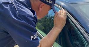 Policjant zagląda przez szybę samochodu