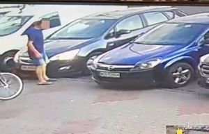 screen z monitoringu, na zdjęciu zaparkowane pojazdy i wizerunek ( twarz zasłonięta) pasażera sprawcy