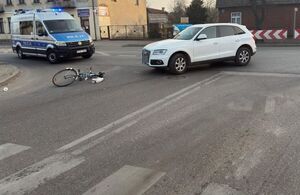 Na zdjęciu policyjny radiowóz, audi i leżący na drodze rower