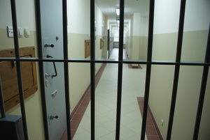 zdjęcie pokazujące korytarz pomieszczenia dla osób zatrzymanych w komendzie miejskiej policji w Ostrołęce (widok z zza zamkniętej kraty)