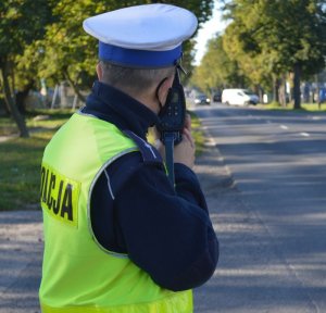 policjant w żółtej kamizelce, który mierzy prędkość pojazdów