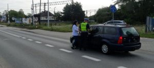 policjant dokonuje kontroli pojazdu na drodze