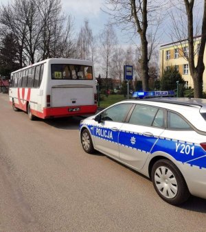 policyjny radiowóz i autobus zaparkowane przed budynkiem szkoły
