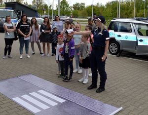policjantka uczy dzieci jak przechodzić przez pasy