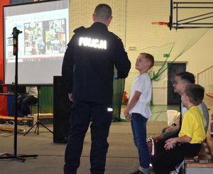 policjant na sali szkolnej zadaje dziecku pytanie