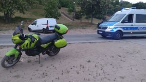 Na zdjęciu widać zielony motocykl, pojazd dacią koloru białego oraz radiowóz