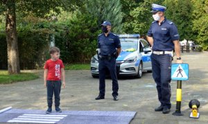 dziecko prezentuje wraz z policjantem bezpieczny sposób przejścia przez pasy