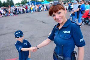 Umundurowana policjantka stojąca obok dziecka w mundurze