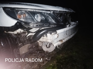 Zdjęcie przedstawia uszkodzony przód samochodu koloru białego.