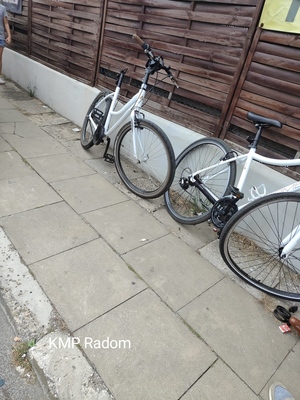 Dwa rowery koloru białego ustawione na chodniku.
