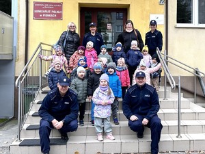 grupa dzieci z opiekunami i policjantami przed budynkiem komisariatu