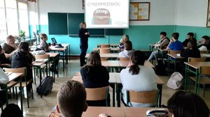 policjantka prowadząca spotkanie w klasie lekcyjnej dla uczniów w tle prezentacja o cyberprzemocy