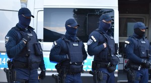 czterech umundurowanych policjantów w czapkach z zasłoniętymi twarzami