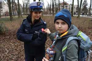chłopiec z puszką przykleja serduszko na kurtce policjantki