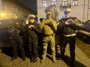 czworo policjantów w różnym umundurowaniu podczas finału WOŚP pokazują serduszko