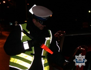 policjant z drogówki w żółtej kamizelce w nocy kontroluje pojazd