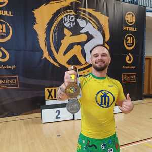 mężczyzna w żółto zielonym sportowym stroju trzyma dwa medale