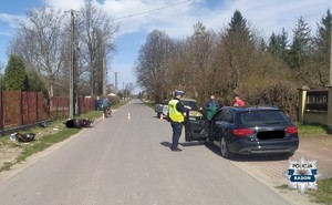 miejsce wypadku w Bierwcach, czarny pojazd na poboczu obok policjant, po drugiej stronie lezy rozbity motocykl