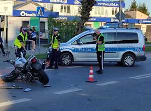3 policjantów pracuje na miejscu wypadku, na drodze leży motocykl, w tle widać radiowóz