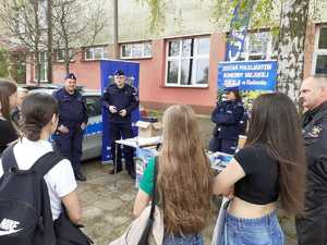 grupa młodziezy przy policyjnym stoisku, rozmawiaja o słuzbie w Policji