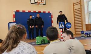policjanci prowadzący prelekcję na sali gimnastycznej, tyłem dzieci