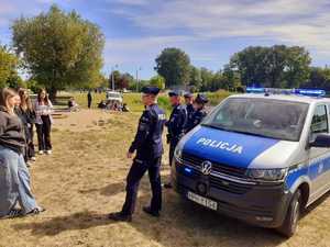 po prawej stronie radiowóz i policjanci stojący bokiem, z lewej strony uczniowie liceum