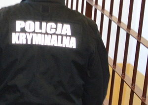 kamizelka czarna  z napisem policja kryminalna w tle kraty