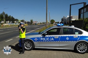 policjantka kontroluje prędkość, stoi przy radiowozie, w tle ulica