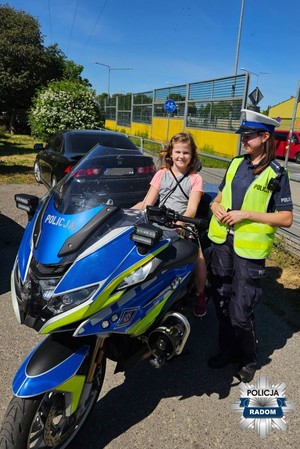 policjantka stoi obok motocykla policyjnego, na którym siedzi dziewczynka