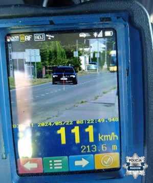 ekran z urządzenia do pomiaru prędkości, wynik 111 km/h w tle samochód