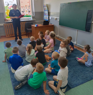 Policjant czytający bajkę dzieciom w klasie siedzi siedzą na dywanie