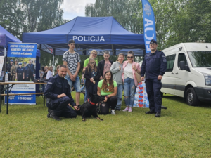 policjanci pozujący z dziećmi przy stoisku profilaktycznym