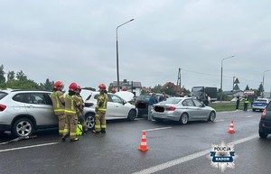 miejsce wypadku, uszkodzone pojazdy, w tle strażacy, policjanci i uczestnicy zdarzenia