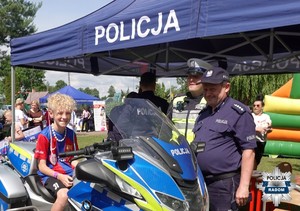 2 policjantów przy motocyklu na którym siedzi chłopiec