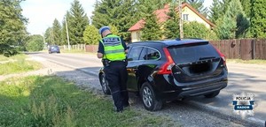 policjant kontroluje kierowcę czarnego pojazdu