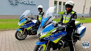 dwaj policjanci na motocyklach przed budynkiem komendy