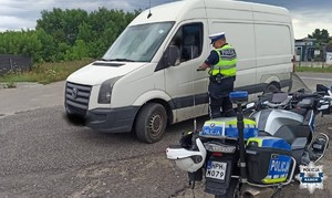 policjant, kontroluje kierowce białego busa, motocykl