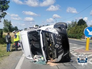 biały bus lezy na boku po wypadku, w tle policjant rozmawia z męzczyzną