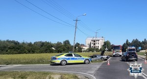 na skrzyżowaniu dwa rozbite samochody w tym jeden zjechał do rowu, po lewej stronie widać radiowóz